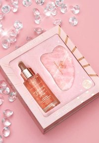 Zestaw do pielęgnacji skóry Crystal Love z gua sha z kwarcu różowego i bursztynowym serum w jasnoróżowym pudełku, z złotymi akcentami i logo.