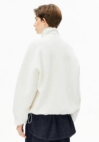 Weißer Fleece-Pullover mit hohem Kragen, überschnittenen Schultern und übergroßer Passform. Verfügt über einen gerafften Saum und eine kontrastierende Denim-Schicht darunter.