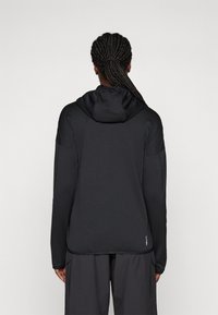 Crna kapuljača jakna, glatka tkanina, dugi rukavi, slim fit dizajn, suptilan logo na rubu, minimalistički stil.