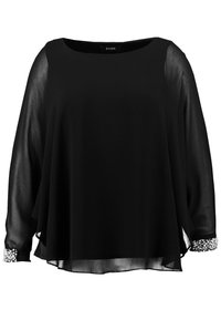 Blouse noire légère avec des manches longues transparentes et un col rond. Présente des poignets ornés d'accents décoratifs.