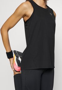 Débardeur athlétique noir avec un col rond, tissu léger et un petit logo sur le haut du côté gauche de la poitrine. Coupe stretch avec des emmanchures accentuées.