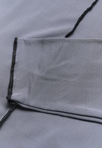 Grauer Stoff mit einer glatten Textur, der am Rand eine schwarze Borte aufweist und leicht zerknittert ist. Insgesamt ein einfaches Design.