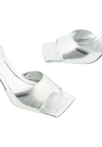 Scarpe con tacco alto metalliche argentate con punta aperta, frontale a taglio quadrato e un design delle cinghie elegante. Texture liscia e accenti minimi.