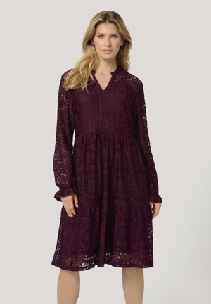 Lace dress in deep burgundy with long sleeves, a V-neck, and a tiered design. Features intricate cutout patterns and gathered sleeve cuffs.