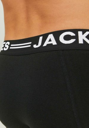 Schwarze Unterwäsche mit einem breiten elastischen Taillenbund, der das Wort "JACK" in Weiß trägt, glatte Stofftextur und flache Nähte.