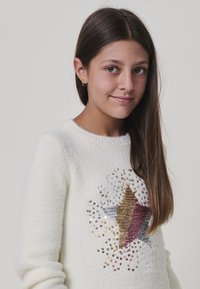 Maglione color crema realizzato in morbido tessuto testurizzato, caratterizzato da un design a stella decorato con paillettes dorate, argento e borgogna.