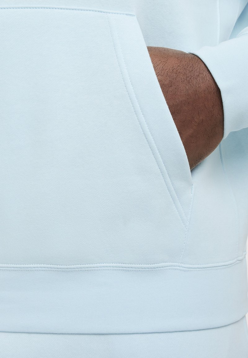 Sudadera de color azul claro con un bolsillo delantero, puños acanalados y dobladillo. La tela tiene una textura suave y un acabado liso.