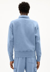 Lichtblauw katoenen sweatshirt met een kraaghals, verlaagde schouders en ribgebreide manchetten. Zachte textuur, relaxte pasvorm en ronde zoom.