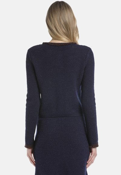 Navy knitted sweater with a textured finish, featuring long sleeves and a fringed trim at the neckline and sleeve cuffs.