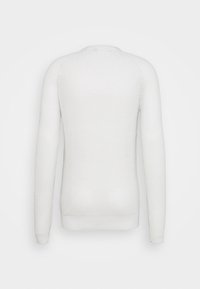 Pull en tricot blanc avec manches longues, encolure ronde et ourlet côtelé. Présente un motif texturé sur l'ensemble du tissu.