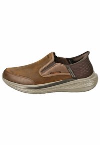 Schlupfschuhe aus braunem Leder mit einer strukturierten Blende, gummierter Sohle und elastischen seitlichen Akzenten für ein einfaches Anziehen.