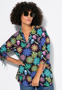 Schwarzes Shirt mit bunten Blumen- und Totenkopfmustern, Dreiviertelärmel mit Bindetails und lockerer Passform.