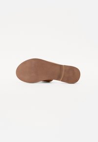Braune Gummisohle mit glatter, leicht strukturierter Oberfläche und runder Form. Verfügt über eine ausgeprägte Absatzkurve und minimalen Details.