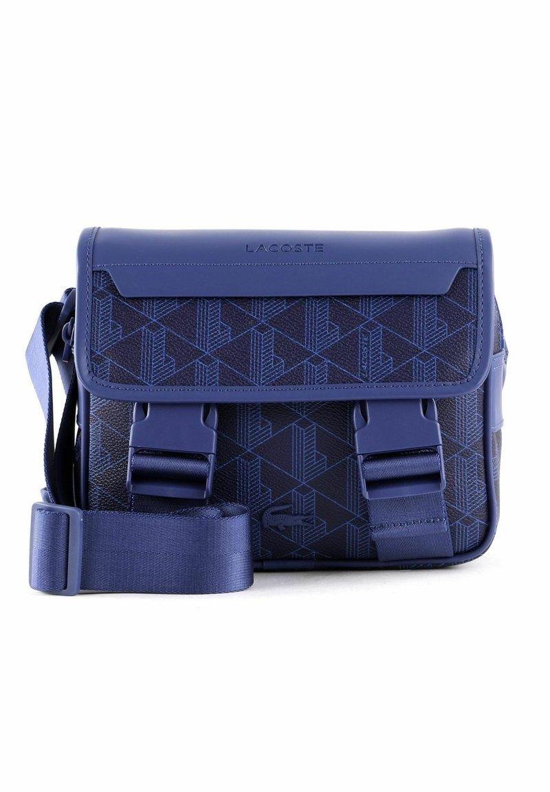 Borsa a tracolla blu Lacoste con motivo geometrico, tracolla regolabile, due chiusure a fibbia frontali e nome del marchio impresso sulla patta.