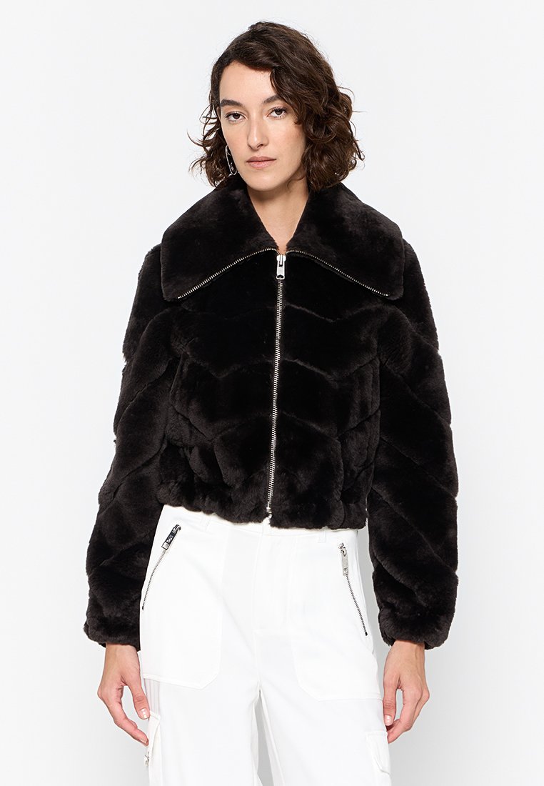 Schwarze Fake-Fur-cropped Jacke mit breitem Kragen, diagonaler Steppung und Front-Reißverschluss. Weiche Textur und voluminöse Silhouette.