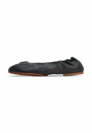 Black leather ballet flat with gathered texture, round toe, and a small bow accent. Features a thin brown sole.