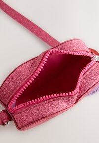 Glittery pink bag with a smooth, shiny exterior. Features a zippered closure with a textured pink zipper pull. Interior lined in matching pink.