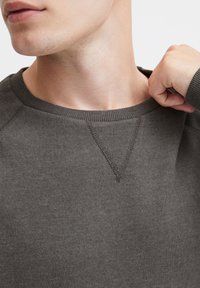 Mørkegrå sweatshirt med ribbet halsudskæring, med v-stik detalje ved kraven og blød tekstur. Ingen synlige mønstre eller accenter.
