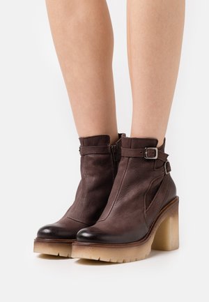 Bottines en cuir marron avec un talon transparent épais, fermeture éclair sur le côté, détail de boucle et bout arrondi. Surface texturée et semelle robuste.