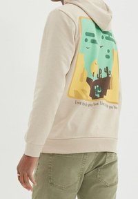 Felpa beige con una grafica colorata che raffigura cactus e montagne, con il testo "Ama la vita che vivi. Vivi la vita che ami." sul retro.