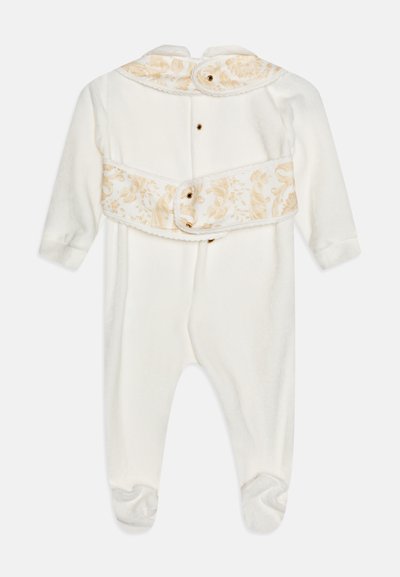 Un body pour bébé blanc en tissu doux, avec des manches longues, un col floral beige décoratif et des fermetures à bouton à l'arrière.