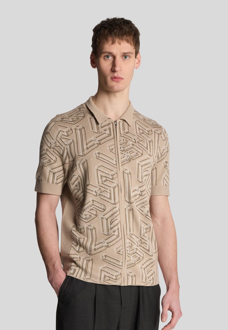 Polo a maniche corte beige con chiusura a zip, caratterizzato da un motivo geometrico testurizzato. Realizzato in tessuto a maglia, presenta un design a colletto classico.
