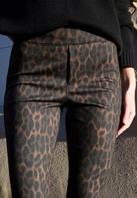 Leopardikuvioiset leggingsit, joissa on sileä, vartalonmyötäinen malli ruskean ja mustan sävyissä, korkea vyötärö ja sivusaumat. Kankaan pinta on teksturoitu.