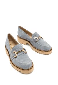 Jasnoniebieskie zamszowe mokasyny z beżową gumową podeszwą, z ozdobnym złotym łańcuchem z przodu oraz przeszyciami wzdłuż krawędzi.