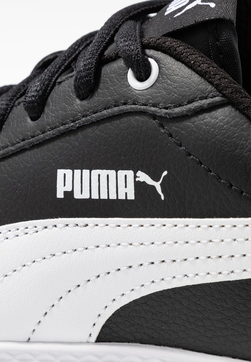 Zapatilla de cuero negro con acentos blancos, con una superficie texturizada, cordones negros y un prominente logo blanco de Puma en el lateral.