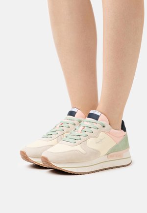 Sneakers med en beige overdel i ruskind, pastelgrønne og rosa accenter, strukturerede snørebånd og en hvid sål med ribbet design.
