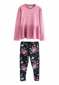 Rosa langærmet top med plisseret kant og teksten "BAKER"; parret med sorte leggings med farverigt blomsterprint og elastisk talje.