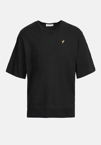 T-shirt en coton noir à manches courtes et col rond. Présente un subtil emblème doré d'oiseau sur la poitrine. Texture douce, coupe décontractée.