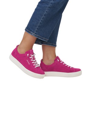 Bright pink suede sneakers with white laces and sole, featuring a rounded toe and minimalistic design, worn with cropped denim pants.