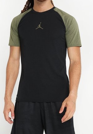 Heren sportt-shirt met een zwart lichaam en olijfgroene raglanmouwen; bevat een subtiele Jumpman-logo op de borst. Zacht, ademend stof.