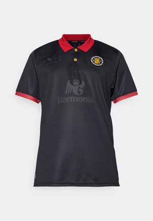 Schwarzes Poloshirt mit rotem Kragen und Bündchen. Mit gelben Knöpfen, gestickten Logos und einem großen grauen Drucklogo auf der Vorderseite.