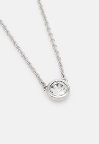 Collier en chaîne argentée avec un pendentif en cristal transparent rond monté dans une bélière en métal poli, mettant en valeur sa texture réfléchissante et son design.