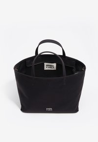 Czarna torba na ramię z płótna z dwoma krótkimi uchwytami, teksturowaną powierzchnią oraz widoczną metką z logo wewnątrz. Otwarta góra z przestronnym wnętrzem.