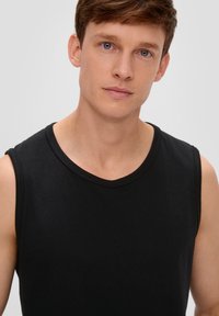Zwarte mouwloze shirt gemaakt van katoen met een ronde hals. Vriendelijke textuur en eenvoudig ontwerp, zonder zichtbare patronen of accenten.