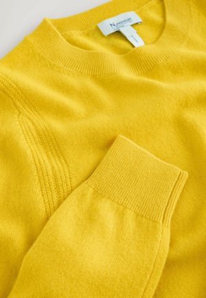 Pulover tricotat galben, cu guler rotund și manșete cu nervuri, având o textură netedă și detalii de cusătură subtile. Eticheta este vizibilă la gât.