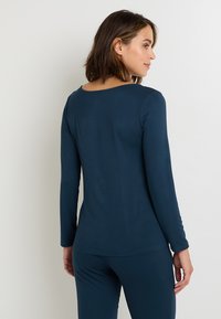 T-shirt à manches longues bleu marine, en tissu doux. Doté d'un col rond et d'une coupe ajustée, il complète l'ensemble du design.