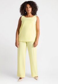 Top giallo senza maniche con scollatura quadrata e pantaloni larghi abbinati gialli. Tessuto morbido con una leggera lucentezza, dettagli minimi.