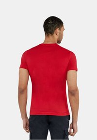 T-shirt rosso a maniche corte realizzato in un tessuto leggero e liscio. Presenta un collo rotondo e un design aderente. La vista posteriore mostra dettagli minimi.