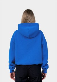 Felpa blu brillante con una finitura testurizzata, maniche lunghe e un grande cappuccio; presenta polsini a coste e una vestibilità rilassata.