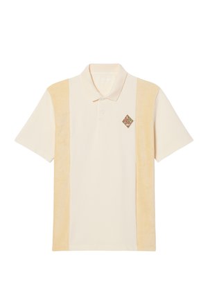 Polo in roomkleur met twee zijpanelen in zacht, lichtgeel. Voorzien van een klein geborduurd diamanten logo in bruin en groen op de borst.