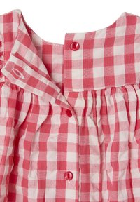 Red and white gingham check, lightweight fabric, ruffled collar, front placket with red buttons, gathered detailing at the neckline.