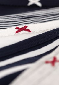 Marine- en witte gestreepte stoflagen met rode decoratieve strikken, voorzien van kantafwerking en een gladde textuur.