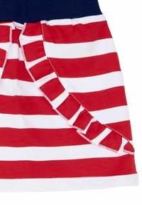 Czerwono-biała spódnica w paski z falbaną po jednej stronie; posiada granatowy pas w talii. Miękka tekstura materiału.