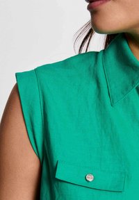 Groen shirt met korte mouwen en kraag, met een gestructureerde stof, knoopzakdetail en een getailleerde pasvorm.