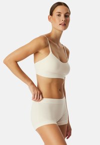 Lys beige bh og short sæt, sømløst design med tynde stropper, blød tekstur og tætsiddende form. Accentueret med et strækbånd i taljen.