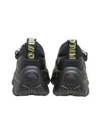 Svarte joggesko med teksturert såle, polstret krage og et gult reim med "BUFFALO"-logo på baksiden. Glatt lær og mesh-materialer.